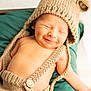 baby, newborn, smiling, knitted_hat, bear_ears, suspenders, green_cushion, closeup, infant, cute, dimples, sleepy, soft_light, portrait, child, peaceful, skin, hand, button, cozy