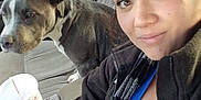 Smoke is registered to the contest to win money with this photo: woman, dog, car_interior, selfie, pet, pitbull, seat, window, drink, canned_beverage, cup, casual, smile, portrait, indoor, daylight, clothing, scarf, hairstyle, parking_lot