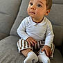 toddler, child, baby, couch, sofa, clothing, white_shirt, striped_pants, socks, indoor, portrait, sitting, cute, curious, young_child, person, face, hands, feet, home