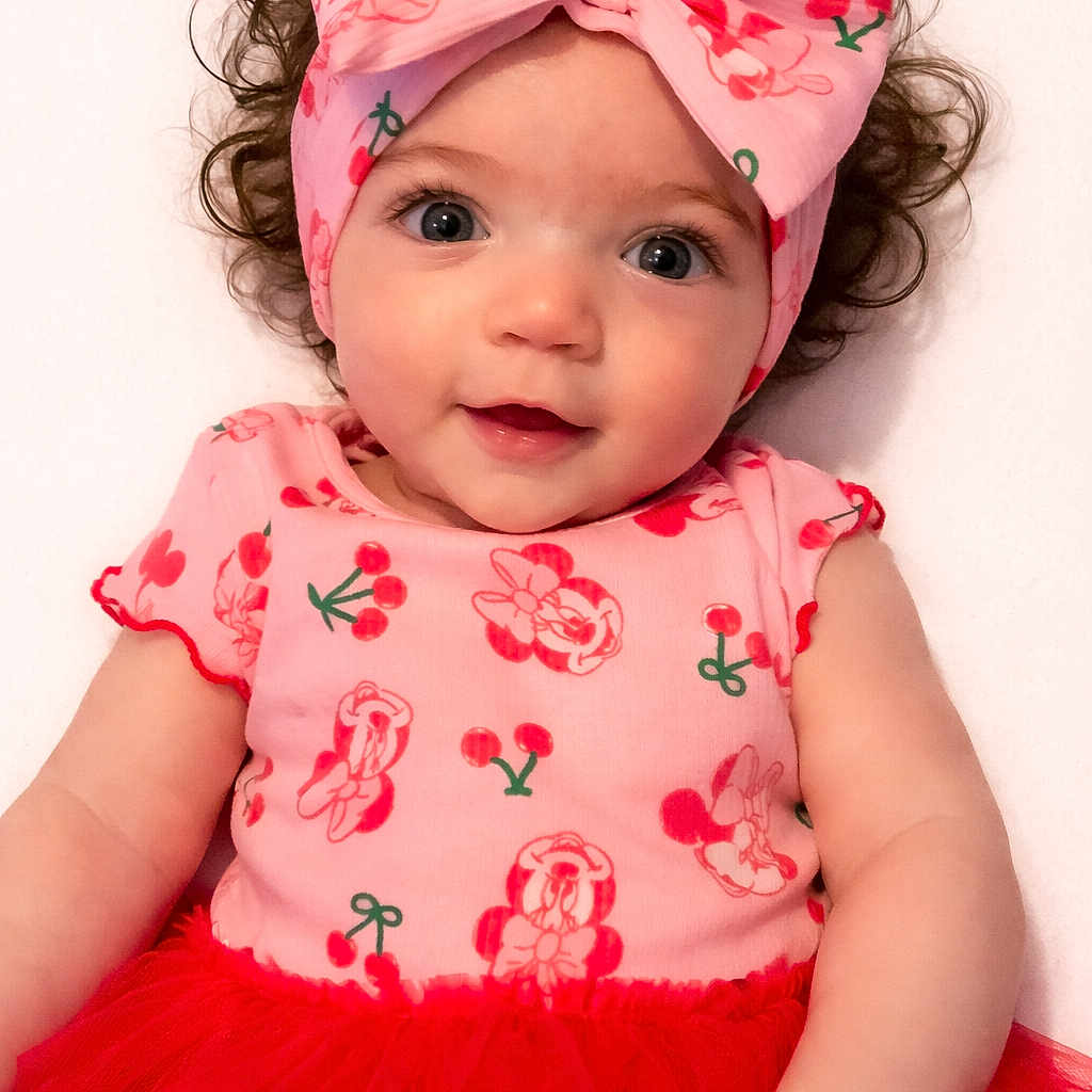 Lillyonna is registered to the contest to win money with this photo: baby, baby_girl, background_white, bow, child, closeup, curly_hair, cute, face, fashion, happy, headband, infant, person, pink_clothing, portrait, red_tutu, smiling, studio, toddler
