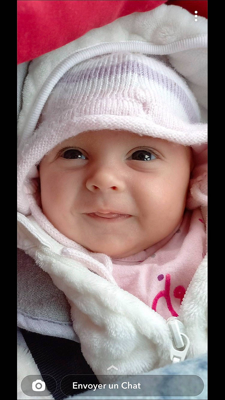 Judith a rejoint le concours — aidez-le/la à gagner de superbes lots ! baby, baby_products, baby_toddler_clothing, cap, cheek, child, facial_expression, fashion_accessory, headgear, headwear, lip, nose, outerwear, person, pink, portrait_photography, product, sleeve, smile, textile