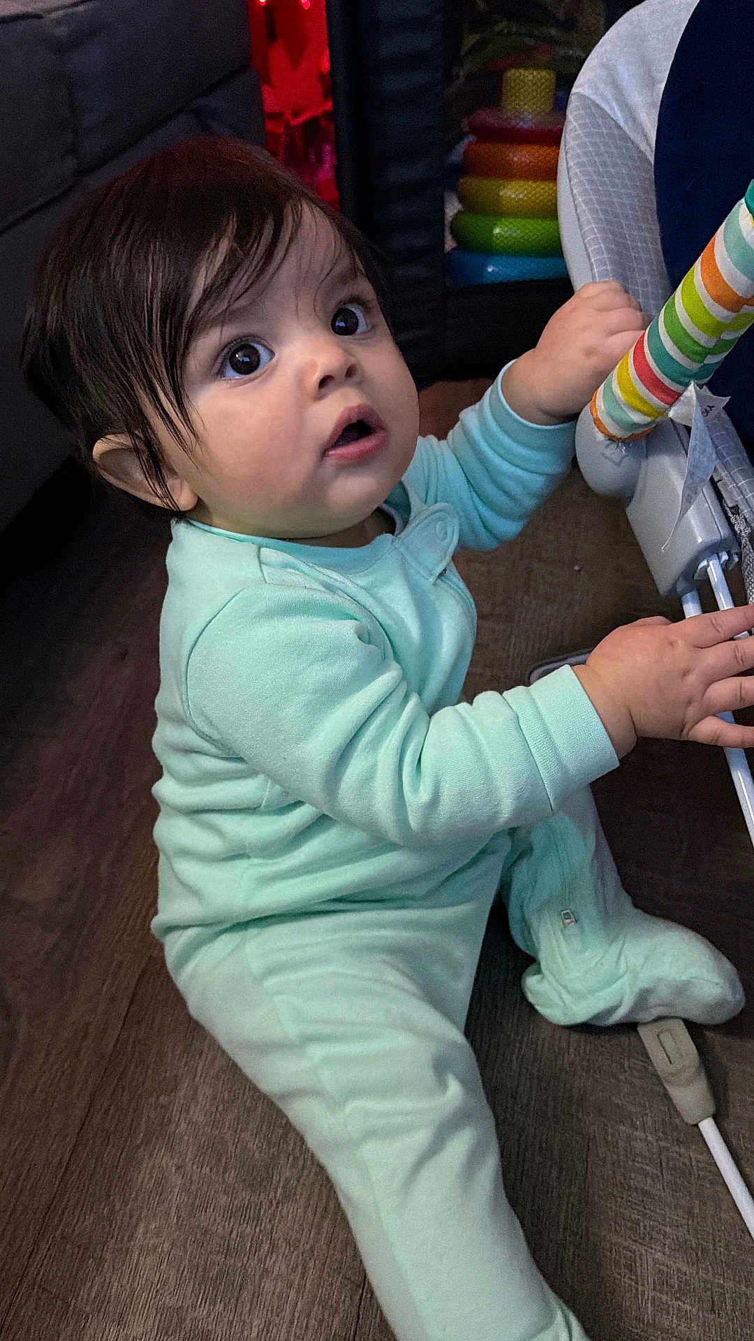 Cartier is registered to the contest to win money with this photo: baby, child, indoor, floor, onesie, toy, colorful, curious, hand, face, expression, person, furniture, wooden_floor, couch, playtime, infant, sitting, closeup, cute