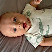 Nathaniel is registered to the contest to win money with this photo: baby, infant, onesie, clothing, lying_down, face, expression, mouth_open, eyes, skin, hand, soft_surface, bed, gray, green, pattern, cute, child, portrait, indoors