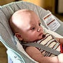 baby, infant, child, rocker, seat, striped_clothing, bald, face, head, arm, indoor, soft_light, cushion, safety_strap, person, young_child, portrait, side_view, calm, seated