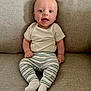 Nathaniel is registered to the contest to win money with this photo: baby, infant, smiling, sitting, couch, striped_pants, white_shirt, socks, happy, indoors, child, face, human, cute, young, portrait, furniture, comfort, casual, expression