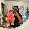 baby, adult, mirror, selfie, nursery, baby_clothing, coral_outfit, hood, white_shoes, wall_art, plant, mobile, crib, furniture, room_decor, person, holding, reflection, indoor, photography