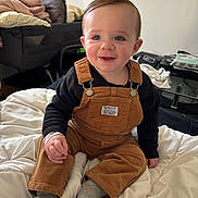 Naëlyo a rejoint le concours — aidez-le/la à gagner de superbes lots ! baby, toddler, child, corduroy_overalls, black_sweater, gray_socks, bed, blanket, pillow, playpen, bassinet, glass_table, magazines, smiling, blue_eyes, rosy_cheeks, indoor, portrait, hand, feet