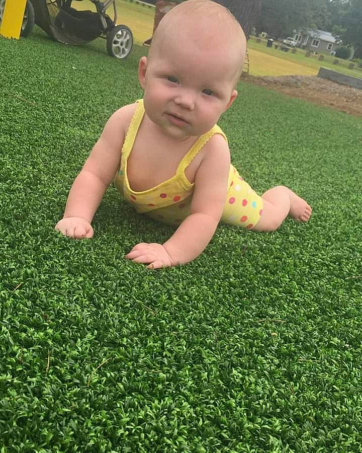 Hailey is registered to the contest to win money with this photo: baby, baby_toddler_clothing, crawling, flooring, grass, grass_family, green, groundcover, hair, happy, leaf, people_in_nature, person, plant, smile, thumb, tire, toddler, tree, wheel