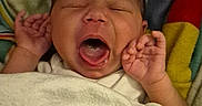 Kairi is registered to the contest to win money with this photo: baby, yawning, blanket, infant, sleepy, hands, face, mouth_open, cozy, colorful_blanket, newborn, wrapped, cute, indoor, portrait, skin, head, small_hands, resting, soft
