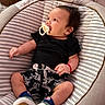 Liam is registered to the contest to win money with this photo: baby, pacifier, infant, black_shirt, patterned_shorts, striped_cushion, baby_seat, socks, white_shoes, indoor, child, cute, relaxed, person, small_hands, head, face, clothing, comfort, looking_away