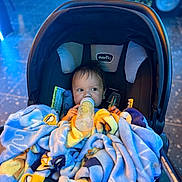 Liam joined the competition — help win amazing prizes! baby, bottle, blanket, car_seat, child, cozy, cute, drink, face, indoor, infant, person, portrait, seat, soft, socks, toddler, warm, young_child, feeding