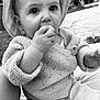baby, child, infant, hat, knit_sweater, hand, face, outdoor, curious, chewing, cute, closeup, portrait, sitting, young_child, soft_lighting, black_and_white, fabric, texture, person