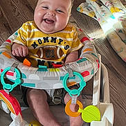 Kamden is registered to the contest to win money with this photo: baby, smiling, infant, child, toy, baby_seat, colorful, floor, blanket, happy, clothing, face, feet, indoors, play, cute, person, seat, wood_floor, teether