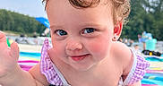 Sophie is registered to the contest to win money with this photo: baby, beach, blue_eyes, child, colorful, curly_hair, cute, daytime, nature, outdoor, playful, portrait, skin, smiling, striped, summer, sunny, toddler, towel, waving