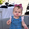 Sophie is registered to the contest to win money with this photo: baby, blue_eyes, chair, child, clothing, couch, cute, denim_overalls, expression, furniture, hands, indoor, napkins, person, pink_headband, pink_shirt, portrait, pouty_face, table, toddler