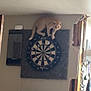 Theo is registered to the contest to win money with this photo: cat, dartboard, wall, ceiling_light, television, chair, wood, exposed_wall, orange_cat, indoor, furniture, curious_cat, perched, room, household_items, technology, screen, light_fixture, animal, pets