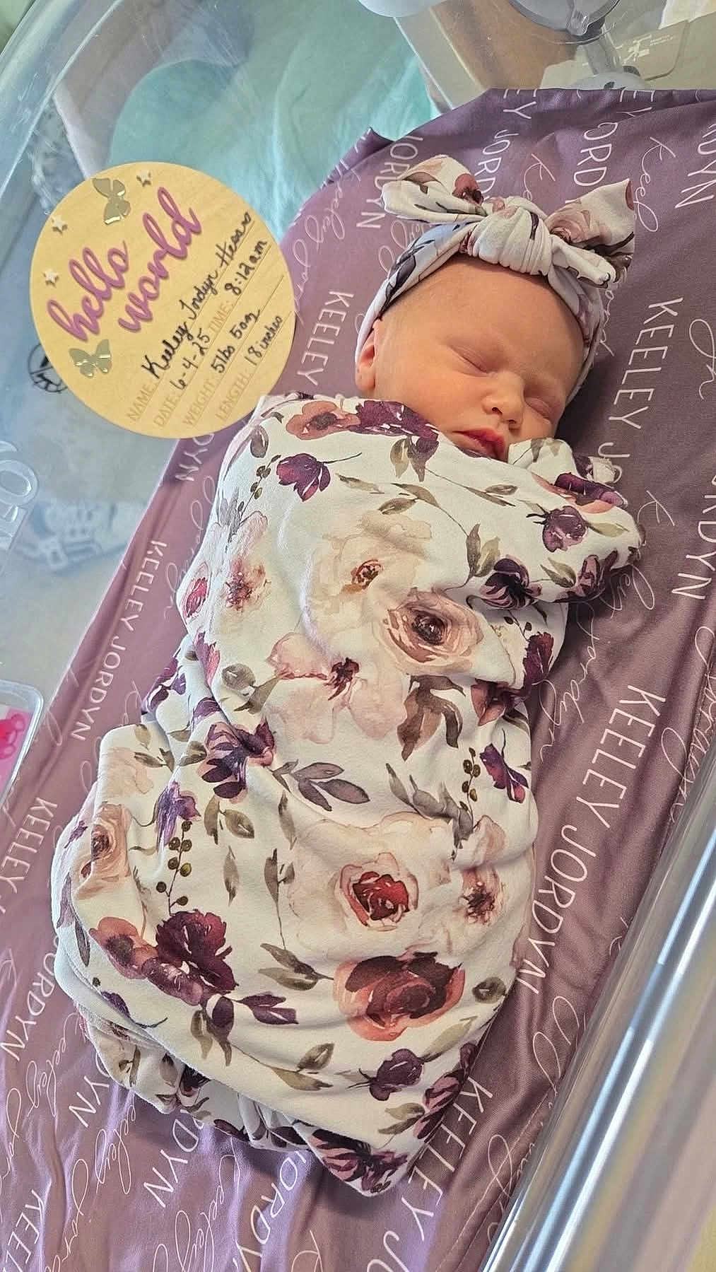 Keeley joined the competition — help win amazing prizes! newborn, baby, sleeping, blanket, headband, floral_pattern, purple, personalized, crib, sign, text, wooden, birth_details, peaceful, indoors, infant, swaddled, cute, resting, portrait