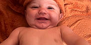 Timélyo participe au concours pour gagner de l'argent avec cette photo : baby, smiling, towel, orange, diaper, happy, child, face, skin, headwear, cute, infant, lying_down, playful, indoors, portrait, chubby_cheeks, expression, young_child, bare_chest