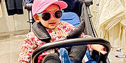 Arwa Musfirah joined the competition — help win amazing prizes! toddler, stroller, pink_cap, sunglasses, blue_cushion, black_socks, floral_shirt, shopping_store, clothing_rack, hanger, casual_clothes, child, indoor, person, footwear, seat, baby, retail, fashion, accessory