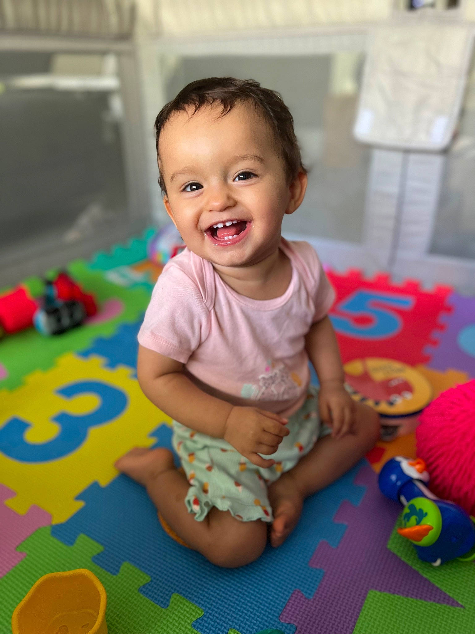 Yüna a rejoint le concours — aidez-le/la à gagner de superbes lots ! baby, baby_playing_with_toys, baby_products, baby_toddler_clothing, cheek, child, flooring, fun, happy, joy, leisure, pattern, person, pink, play, room, sitting, skin, smile, toddler