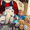 baby, plush_toy, stuffed_animal, blue_bunny, beige_bunny, clothing, blanket, indoor, child, toddler, toy, face, person, decor, fabric, sitting, cute, soft, holiday, room