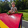 blue_sky, boy, child, clouds, forest, grass, happy, outdoor, park, play, play_equipment, playground, portrait, red, sitting, summer, sunlight, toddler, trees, yellow