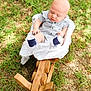 baby, infant, child, outdoor, grass, wood, rocking_chair, clothing, socks, striped_outfit, nature, sunlight, seat, person, baby_boy, head, face, hands, ground, daytime