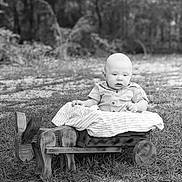 Brayden is registered to the contest to win money with this photo: baby, child, outdoor, wooden_cart, grass, blanket, black_and_white, portrait, infant, nature, cute, toy, small_cart, sitting, face, head, clothing, ground, tree, photography