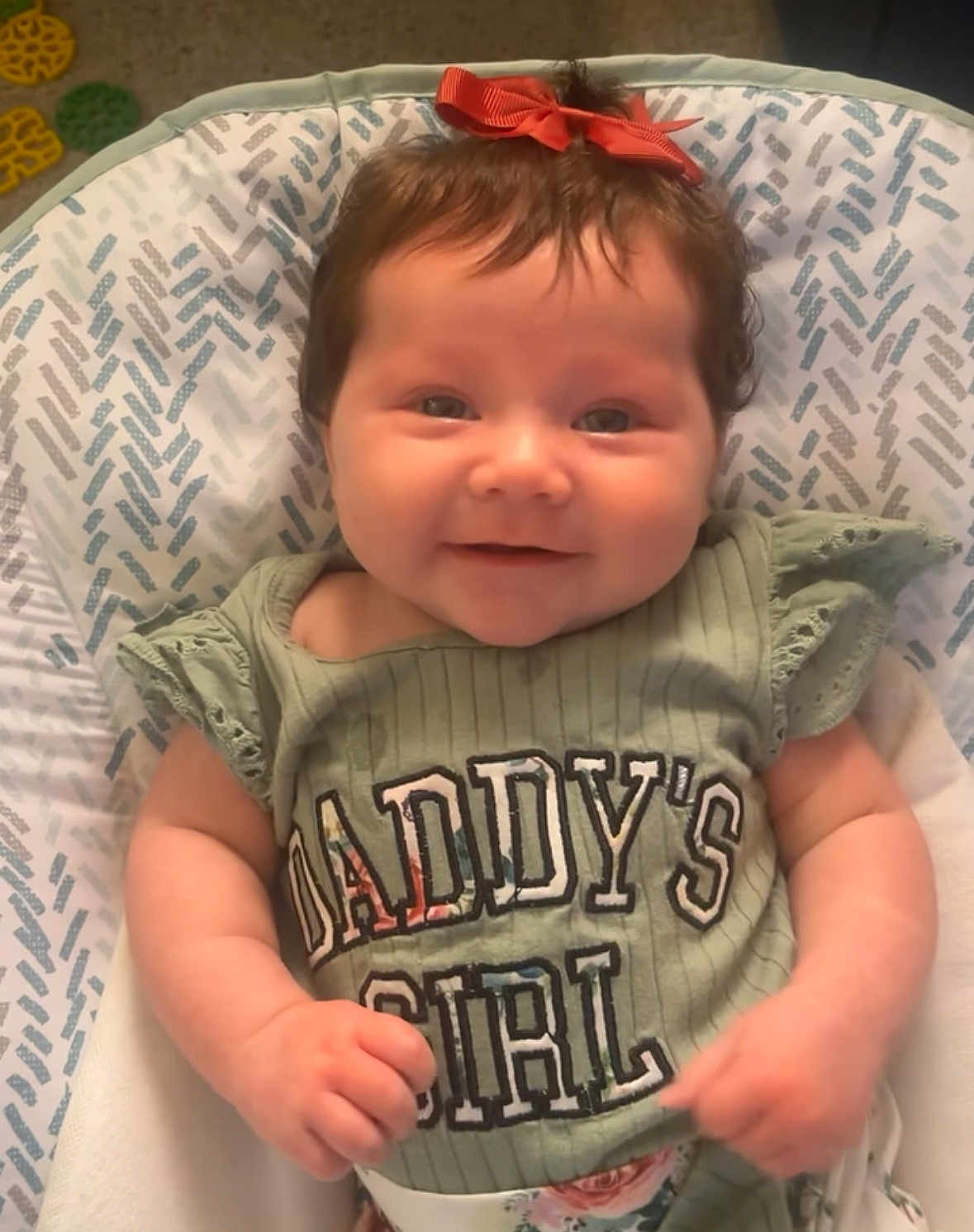 Alivia Isaac joined the competition — help win amazing prizes! baby, child, smiling, bow, green_shirt, text, daddys_girl, infant, cute, happy, sitting, patterned_seat, indoor, portrait, young_child, clothing, person, face, hand, head