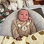 baby, infant, blanket, stuffed_animals, plush_toys, cushion, bed, bear_pattern, clothing, soft_toys, cute, indoor, child, person, comfort, sleeping_area, smile, head, face, rest