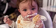 Averie-Grace is registered to the contest to win money with this photo: toddler, child, high_chair, cookie, cream, messy, face, hands, food, snack_time, baby, bib, indoor, cute, expression, clothing, person, feeding, fun, playful