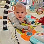 Luc is registered to the contest to win money with this photo: baby, child, infant, play_mat, toy, colorful, hanging_toy, indoor, carpet, cute, smiling, face, person, clothing, early_learning, tummy_time, expression, bright, happy, floor