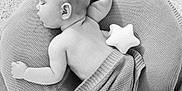 Luc is registered to the contest to win money with this photo: baby, sleeping, blanket, cushion, plush_toy, star, knitted, soft, peaceful, infant, resting, indoors, portrait, child, cozy, bare_skin, carpet, cute, head, relaxing