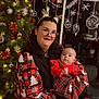 Maïssa a rejoint le concours — aidez-le/la à gagner de superbes lots ! christmas_tree, woman, baby, glasses, reindeer_antlers, red_clothing, plaid_pattern, holiday_decorations, ornaments, lights, smiling, indoor, festive, holding, person, face, headwear, floor, window, seasonal