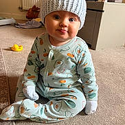 Denny James joined the competition — help win amazing prizes! baby, child, infant, onesie, hat, carpet, indoor, toy, rubber_duck, face, expression, cute, sitting, home, cozy, knit_hat, patterned_clothing, tongue_out, soft_light, domestic