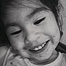 child, smiling, portrait, close_up, black_and_white, face, head, hair, eyes, teeth, happy, indoors, casual, shirt, patterned_clothing, candid, looking_at_camera, young, person, photography