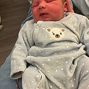 Gabriel participe au concours pour gagner de l'argent avec cette photo : newborn, baby, infant, onesie, star_pattern, bear_patch, sleeping, person, jeans, lap, indoors, floor, wires, comfort, clothing, cute, cozy, skin, head, hand