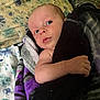 Salem is registered to the contest to win money with this photo: baby, newborn, blanket, bed, floral_pattern, person, infant, face, skin, hand, wrapped, cozy, sleeping_area, soft_texture, indoor, resting, cute, curious, lying_down, comfort