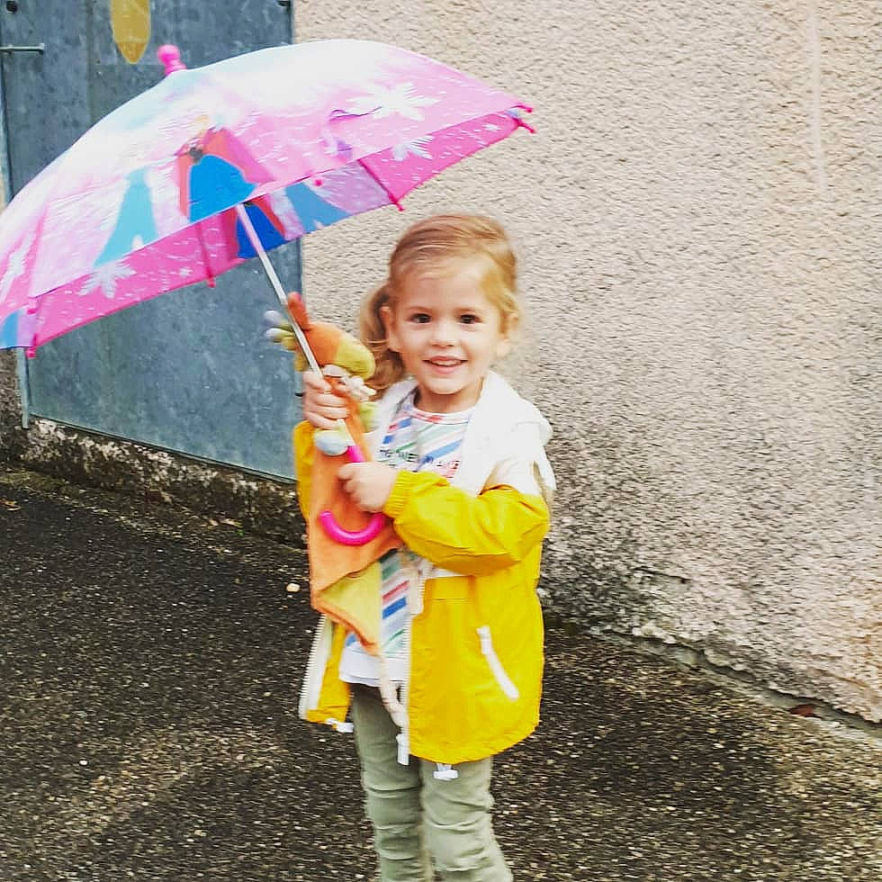 Léa participe au concours pour gagner de l'argent avec cette photo : child, fashion_accessory, joy, outerwear, person, pink, play, rain, smile, toddler, umbrella