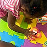 Paris is registered to the contest to win money with this photo: child, toddler, toy, spinning_toy, hand, colorful_mat, foam_puzzle, striped_shirt, pink_shorts, indoor, playtime, curious, crawling, person, kids_play, bright_colors, floor_play, young_child, casual_clothing, early_learning