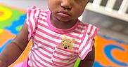 Paris joined the competition — help win amazing prizes! toddler, child, indoor, playmat, colorful, pink_clothing, striped_shirt, bear_patch, serious_expression, hair_buns, crib, wooden_dresser, toy, floor_mat, playroom, person, portrait, sitting, young_child, casual