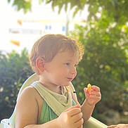 Sasha participe au concours pour gagner de l'argent avec cette photo : toddler, child, high_chair, food, outdoor, greenery, sunlight, cute, smiling, baby, person, small_hand, summer, nature, portrait, happy, clothing, bib, curly_hair, daylight
