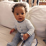 Ewan participe au concours pour gagner de l'argent avec cette photo : baby, child, indoor, couch, blanket, curly_hair, pajamas, face, person, furniture, plant, home, seated, cozy, cute, expression, hand, footed_pajamas, living_room, smile