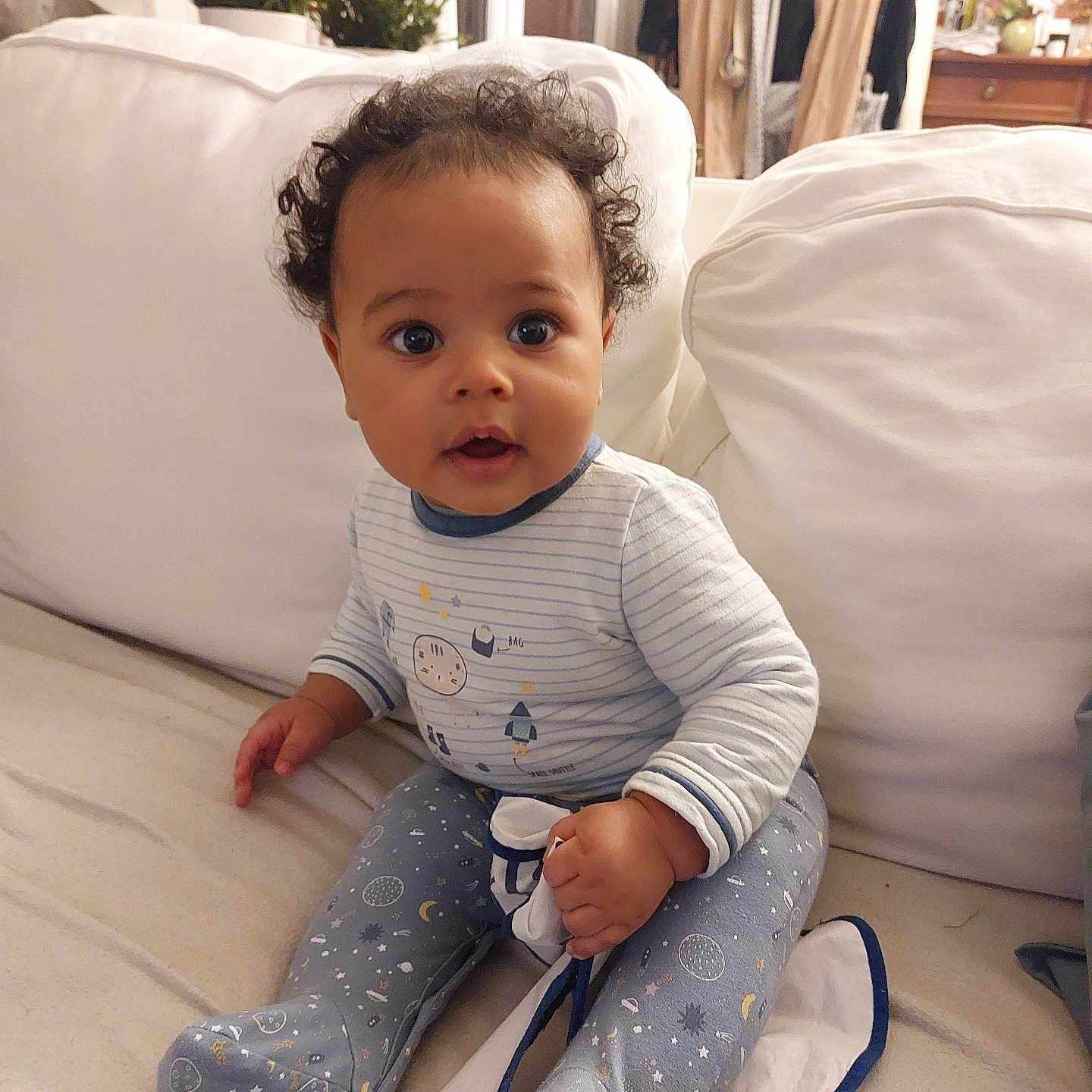 Ewan participe au concours pour gagner de l'argent avec cette photo : baby, blanket, child, couch, cozy, curly_hair, cute, expression, face, footed_pajamas, furniture, hand, home, indoor, living_room, pajamas, person, plant, seated, smile