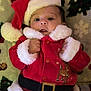baby, child, santa_hat, santa_costume, holiday, christmas, festive, red_clothing, fur_trim, infant, blanket, pattern, smiling, cute, portrait, indoors, holiday_season, young_child, festive_outfit, christmas_decor