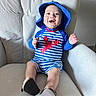 baby, child, smiling, blue_hat, striped_clothing, lobster_design, armchair, indoor, happy, cute, infant, footwear, baby_clothes, hat, person, seated, portrait, furniture, light, texture