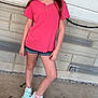 brick_wall, casual_clothing, child, concrete_floor, coral_shirt, denim_shorts, earrings, feet, freckles, girl, happy, legs, long_hair, mint_green, outdoor, portrait, posing, smile, sneakers, standing