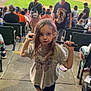 child, girl, baseball, bat, stadium, crowd, sports, outdoor, casual_clothing, shorts, tshirt, pink_shoes, concrete, seating, people, game, daylight, fun, playful, spectators