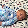 baby, infant, onesie, blue, floral_pattern, blanket, footprints, lying_down, face, head, person, newborn, sleepwear, soft, cute, indoors, child, toddler, clothing, expression
