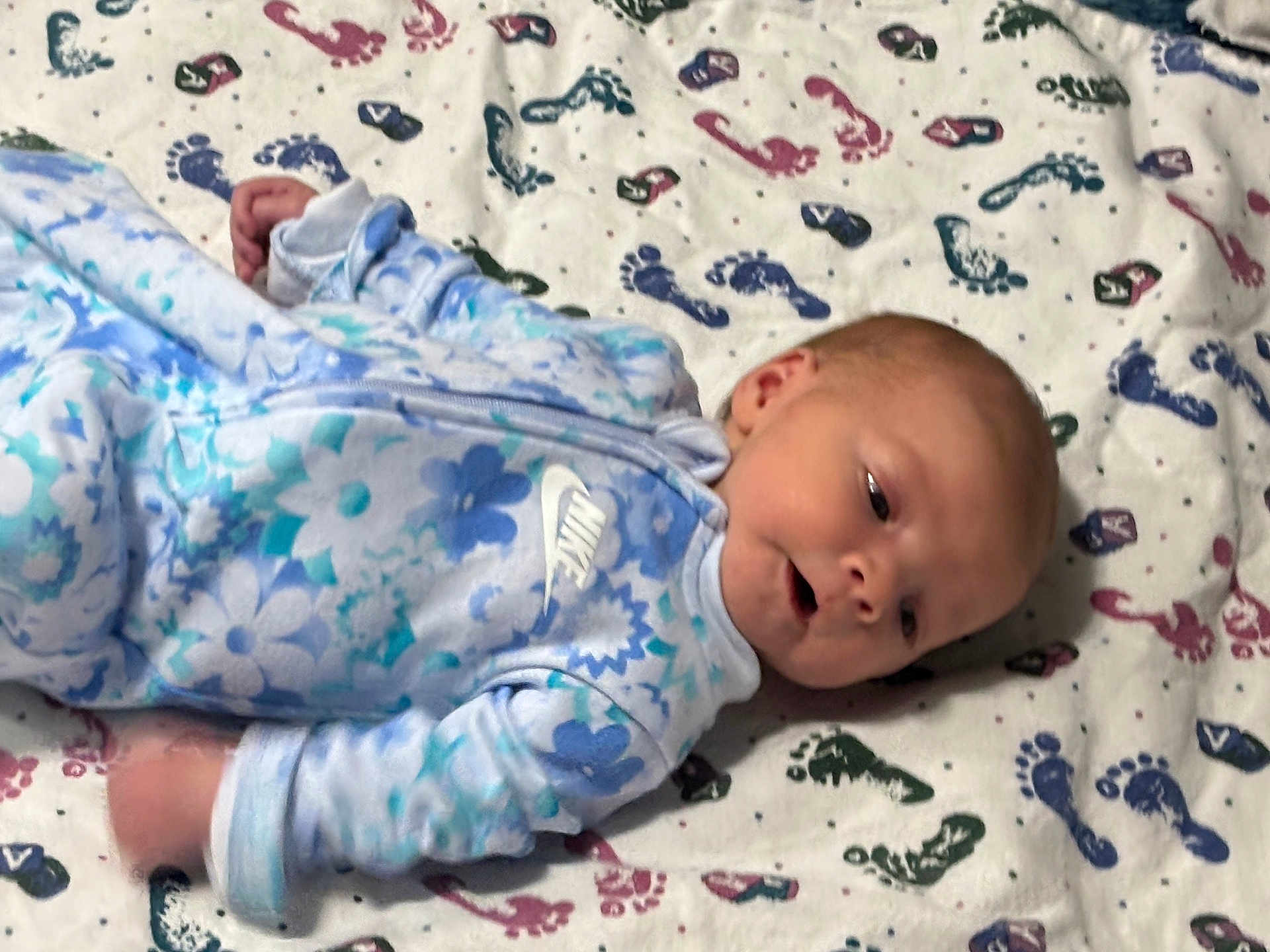 Tyler joined the competition — help win amazing prizes! baby, infant, onesie, blue, floral_pattern, blanket, footprints, lying_down, face, head, person, newborn, sleepwear, soft, cute, indoors, child, toddler, clothing, expression